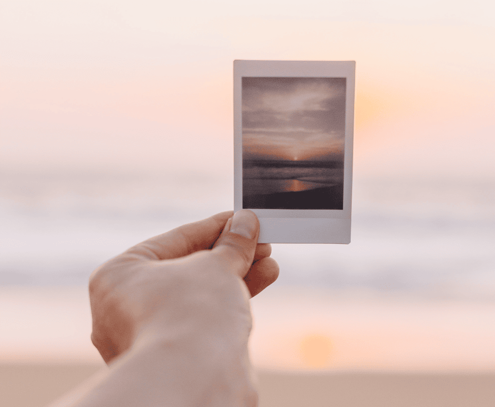 person holding picture in front on a sunset for an article about low effort side hustles